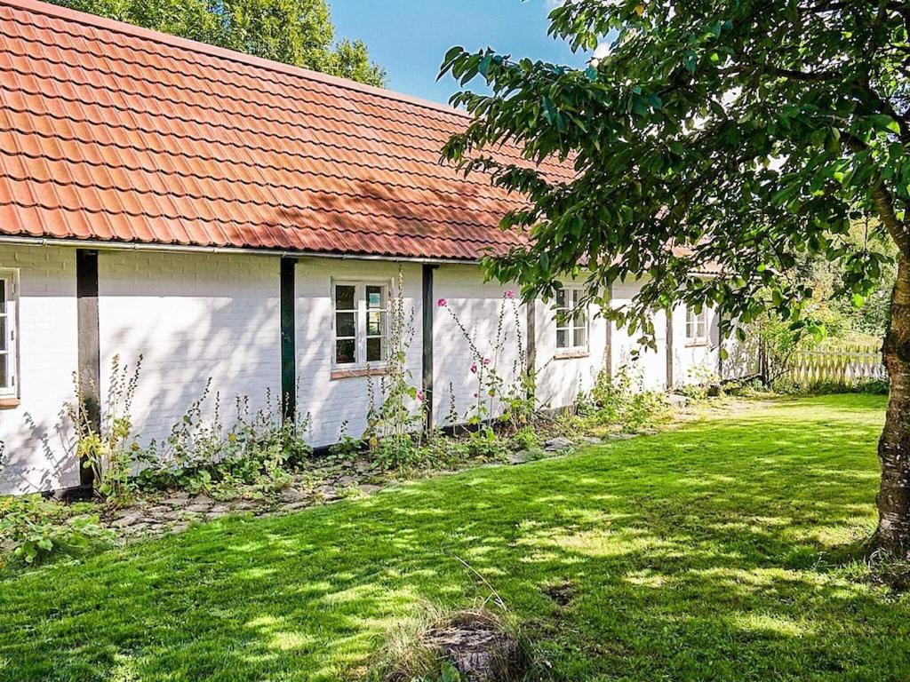 een wit gebouw met een oranje dak en een tuin bij 5 person holiday home in Aakirkeby in Åkirkeby
