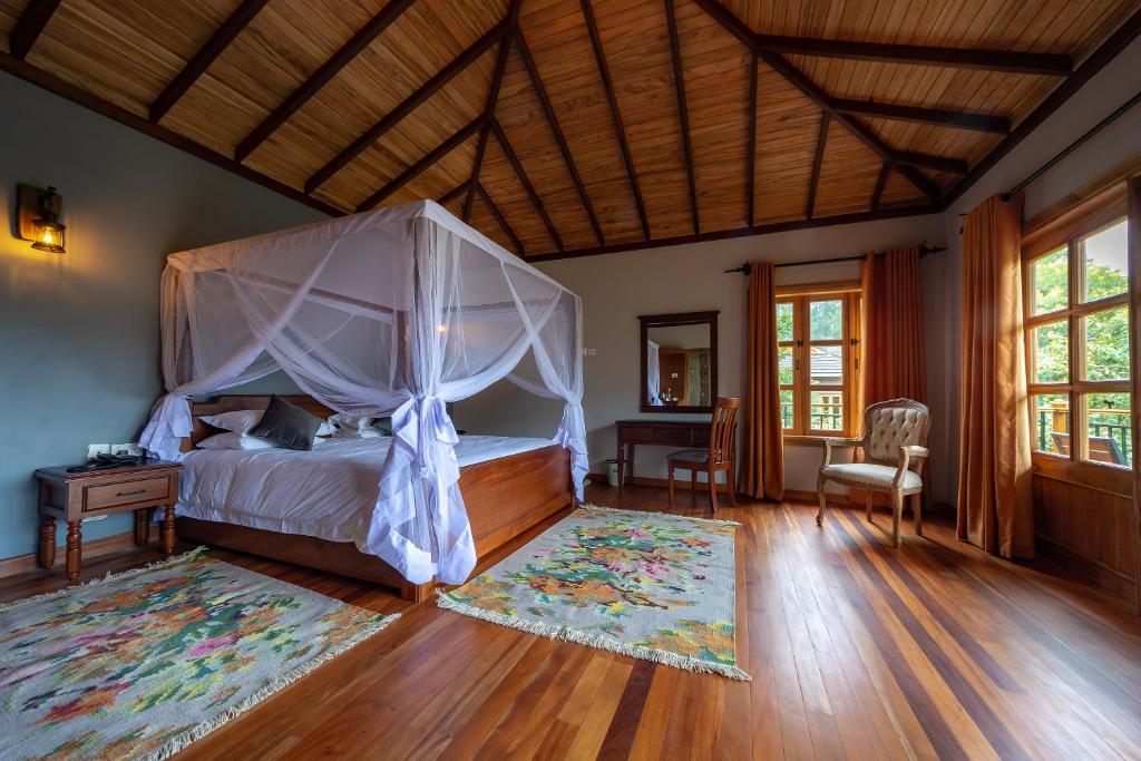 a bedroom with a canopy bed and a wooden floor at Chimpundu Lodge in Fort Portal