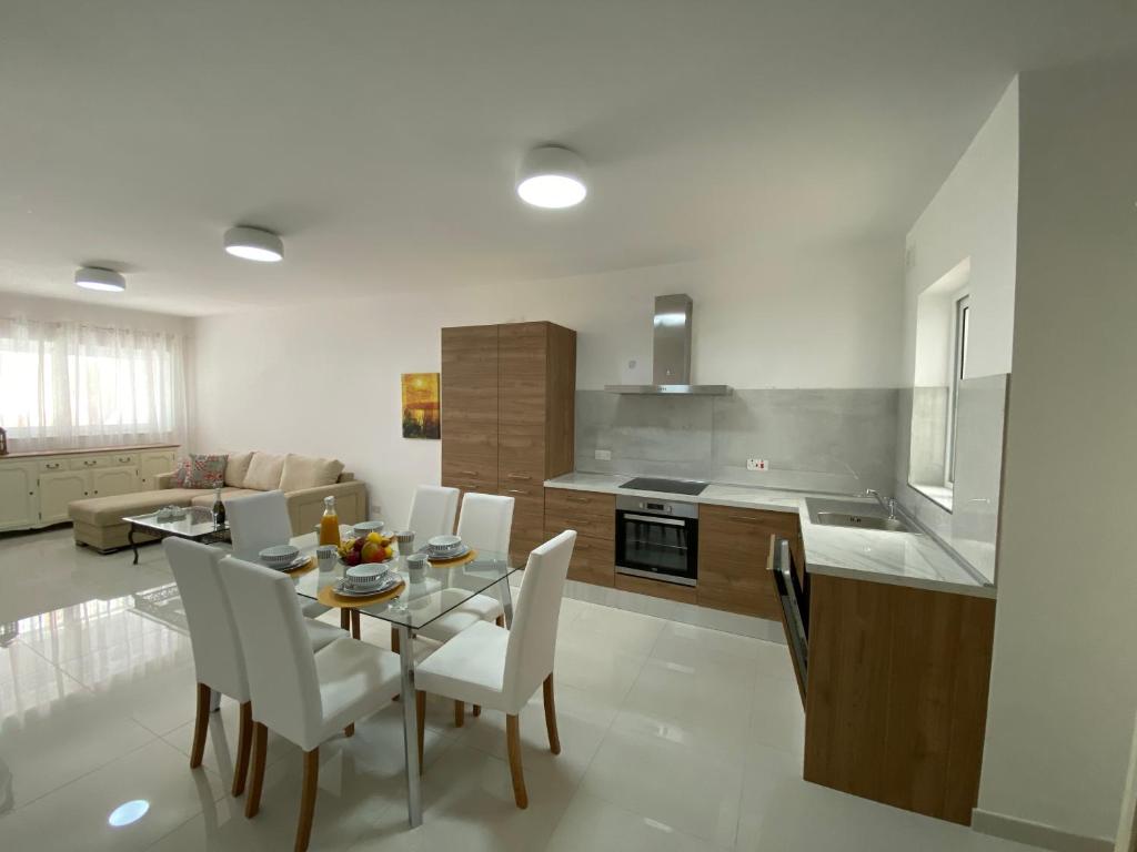 eine Küche und ein Esszimmer mit einem Tisch und Stühlen in der Unterkunft Sunshine Apartments Mellieha - modern three bedroom ground floor apartment with yard in Mellieħa