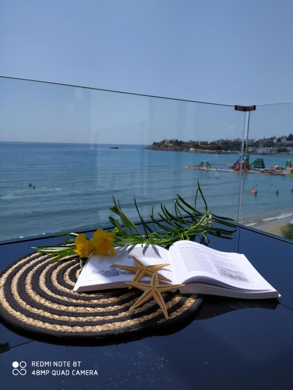 une table avec un livre ouvert, une étoile de mer et un livre sidx sidx sidx dans l'établissement AKTIS MAKRIGIALOS LUXURY APTS, à Makry Gialos