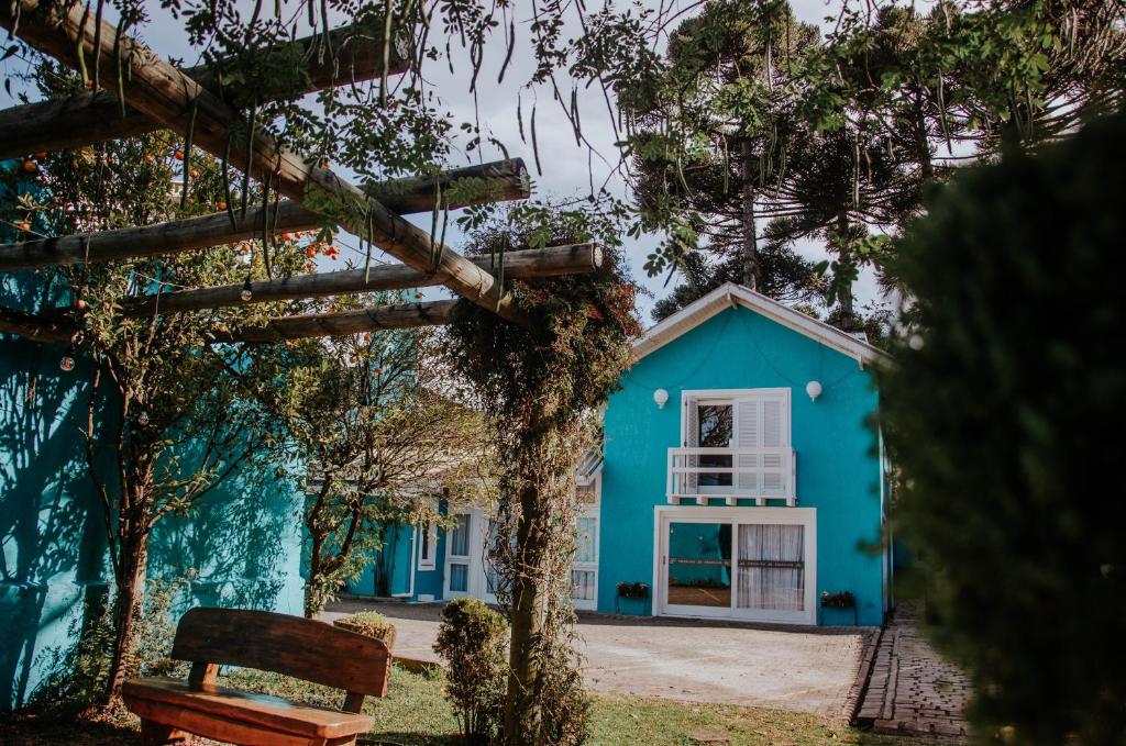 una casa azul con un banco delante en Pousada Lanai Gramado, en Gramado