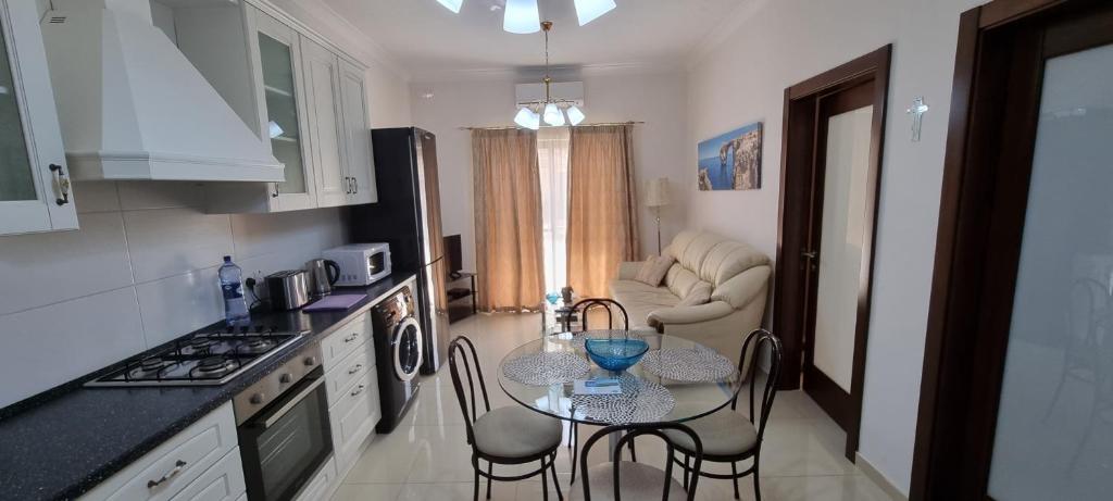 a kitchen with a table and chairs in a room at Munxar Holiday Apartment in Marsaskala