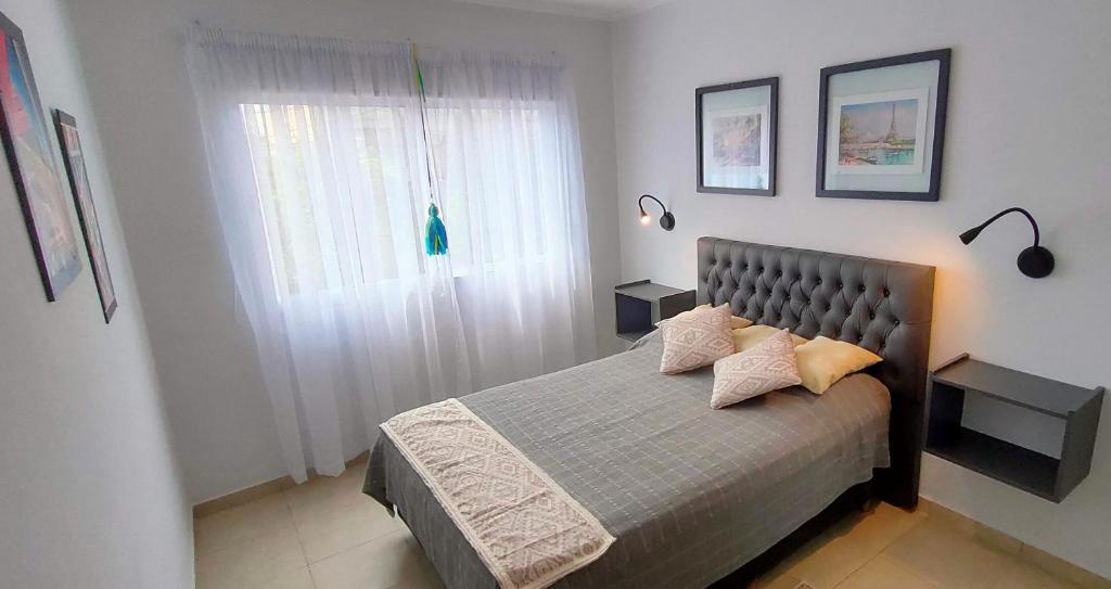 1 dormitorio con 1 cama con 2 almohadas y ventana en Apart Polonia II en San Miguel de Tucumán