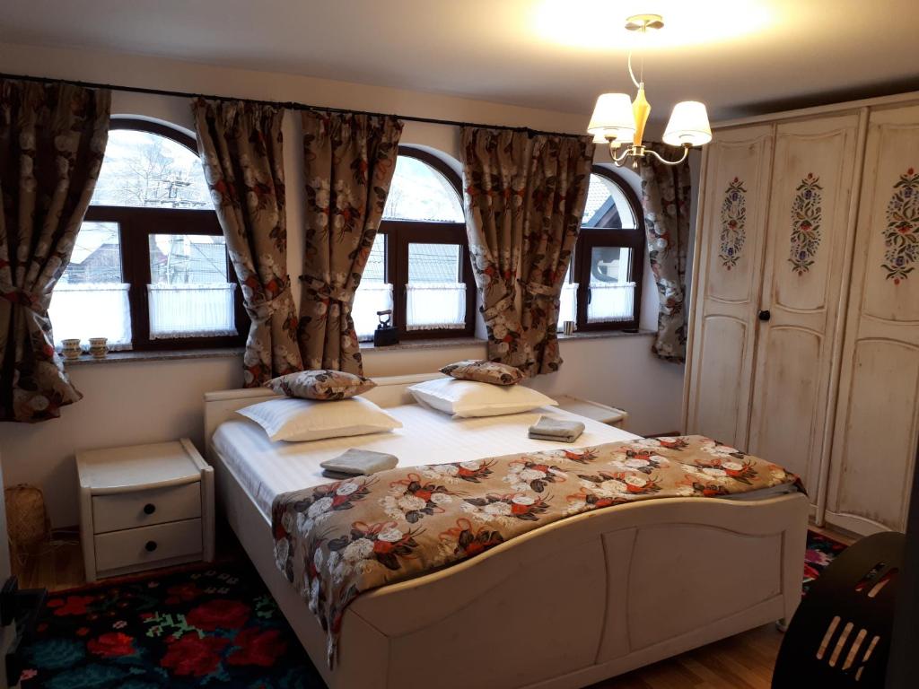 a bedroom with a large bed in a room with windows at Feel Free House in Stulpicani