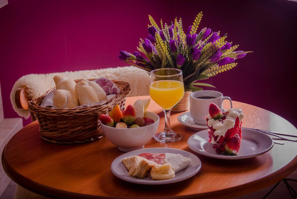 una mesa con platos de comida y una cesta de fruta en Pousada Mima en Gramado