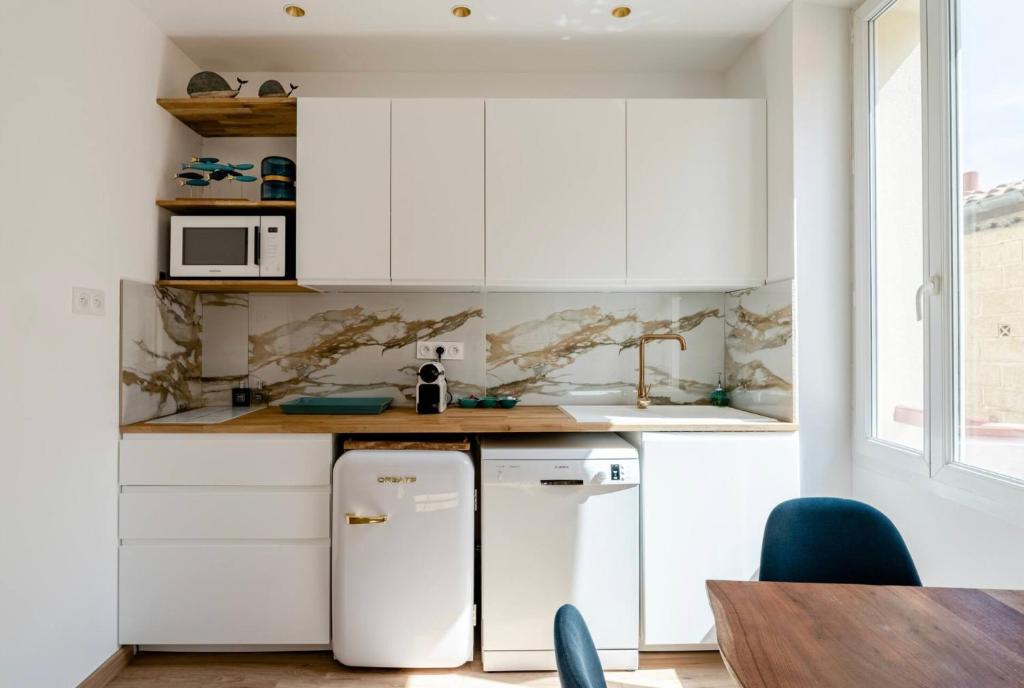 a kitchen with white cabinets and a refrigerator at Appartement le Quai du Port Cassis parking clim in Cassis