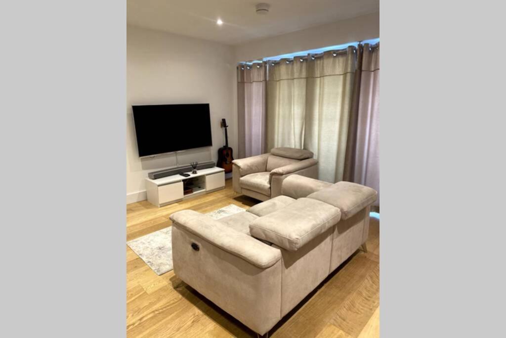 a living room with a couch and a flat screen tv at Luxury 1 Bedroom Apartment with Netflix & Parking in Borehamwood