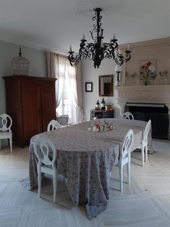 a dining room with a table with chairs and a chandelier at Maison Coqueréaumont in Montagne