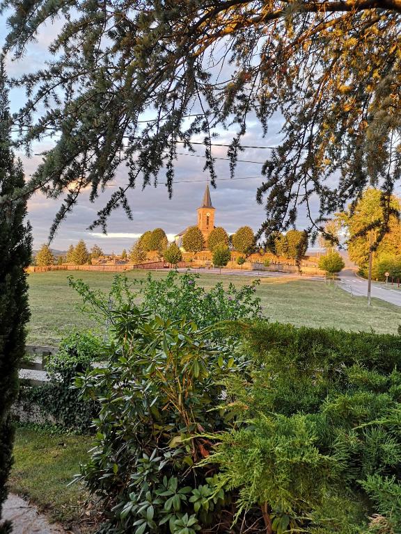 - une vue sur un champ avec une église au loin dans l'établissement LE CEDRE BLEU, à Saint-Michel-sur-Meurthe