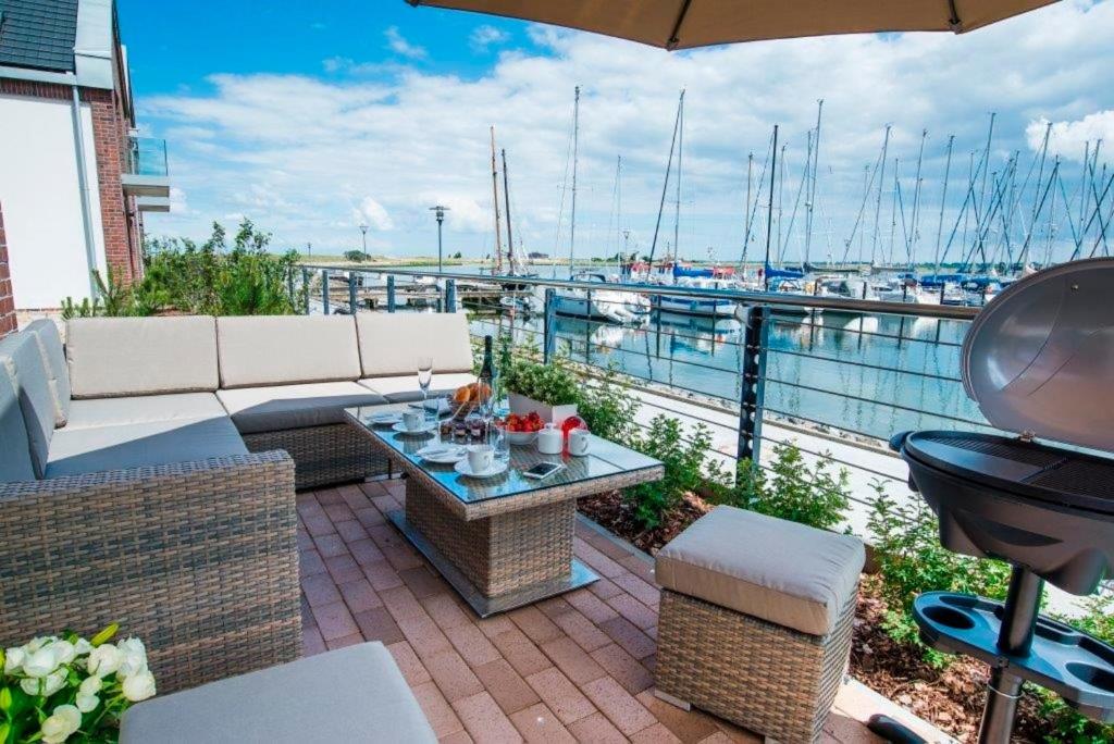 a patio with a couch and a table and a grill at Ostsee - Maisonette - Appartement Nr 54 "Marina-Blick" im Strand Resort in Heiligenhafen