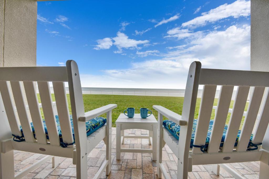 2 sillas y una mesa en un patio con vistas al océano en Sandy Sunrise - 1040S, en Port Orange