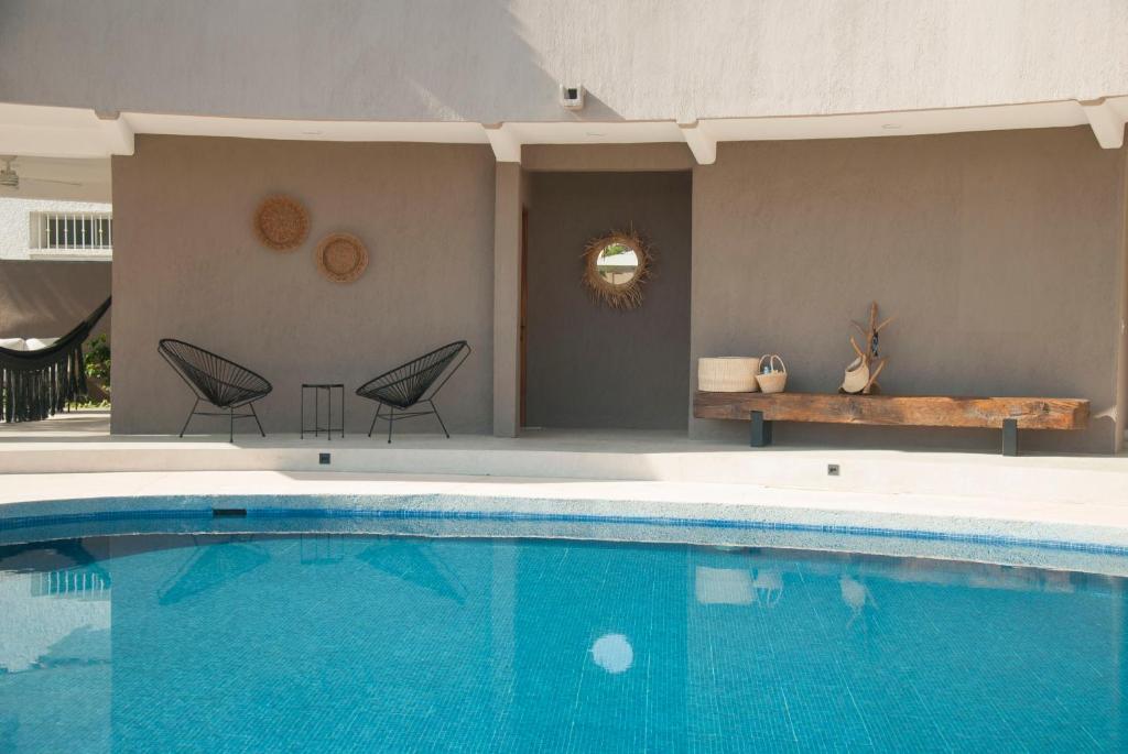 una gran piscina con 2 sillas y un banco en Casa Lulú en San José del Cabo