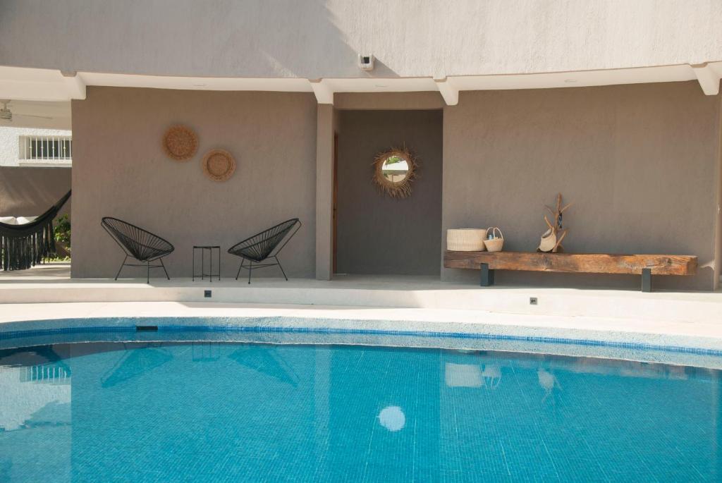 a large swimming pool with two chairs and a bench at Casa Lulú in San José del Cabo