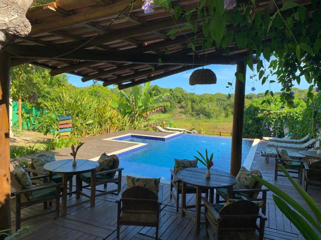 a patio with tables and chairs and a swimming pool at Villa Nobre Diniglei in Trancoso