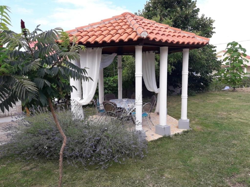 a gazebo with a table and chairs in a yard at Apartment Pavilion-beautiful garden in Kampor