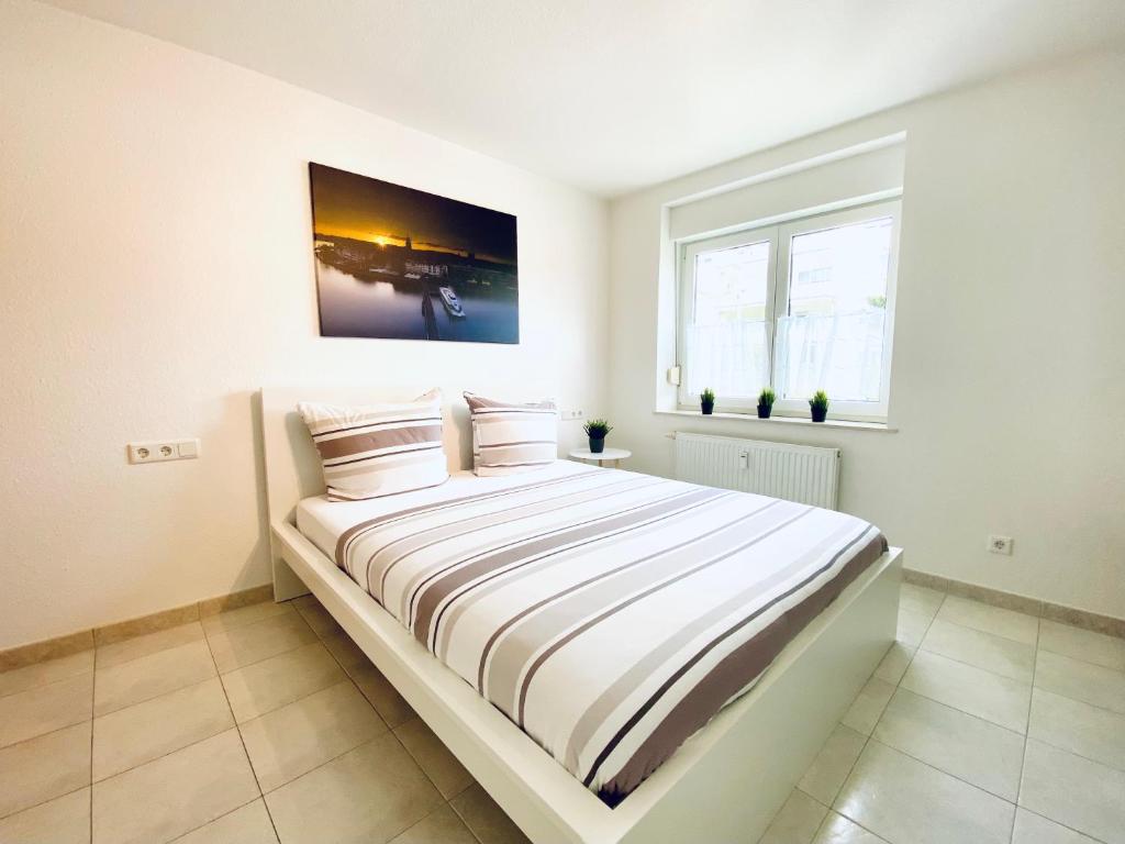 1 dormitorio blanco con 1 cama grande con sábanas a rayas en Auszeit Apartment BODENSEE mit 4 Schlafzimmern, 600 m Luftlinie bis zum Bodenseeufer, in unmittelbarer Nähe des Bodenseeradwegs, schöne Sonnenterrasse, schnelles Internet, für bis zu 5 Personen en Friedrichshafen