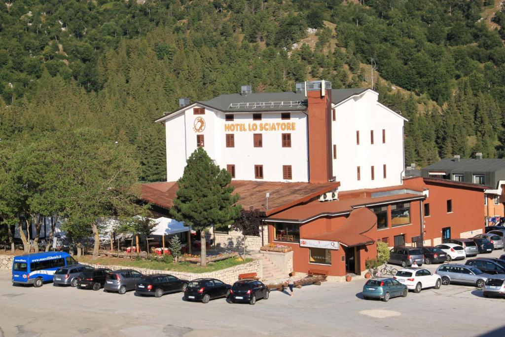 a large building with cars parked in a parking lot at Club Hotel Lo Sciatore in San Massimo