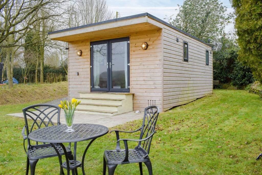 a small cabin with a table and chairs in front of it at Secluded Log Cabin in beautiful private gardens 