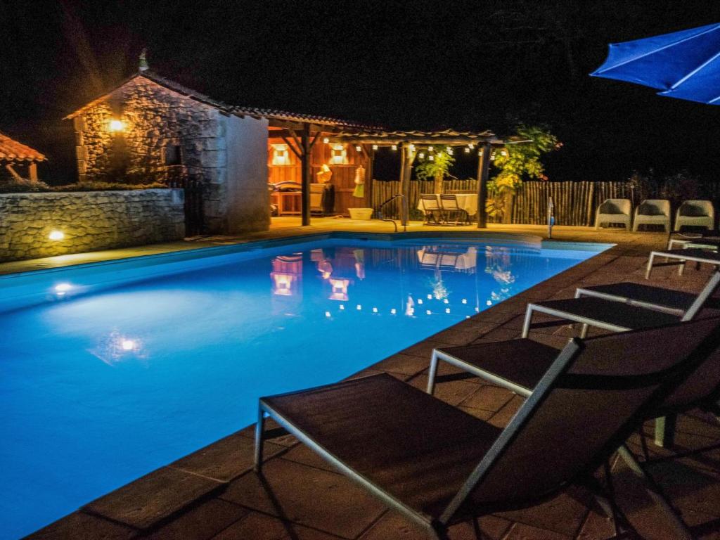 ein Pool in der Nacht mit zwei Stühlen und einem Sonnenschirm in der Unterkunft Gapard La Grange in Issac