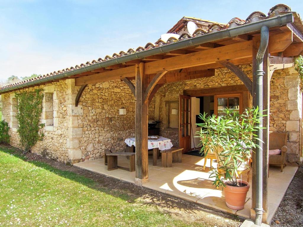 ein Steinhaus mit einer hölzernen Pergola in der Unterkunft La petit Gapard in Issac