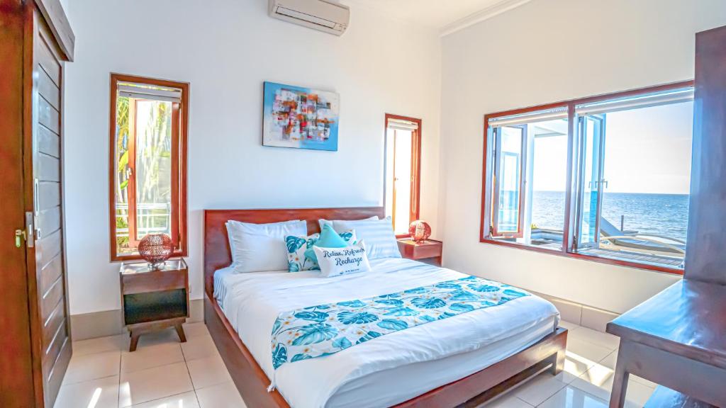a bedroom with a bed with a view of the ocean at Air Sanih Beach Villa in Kubutambahan