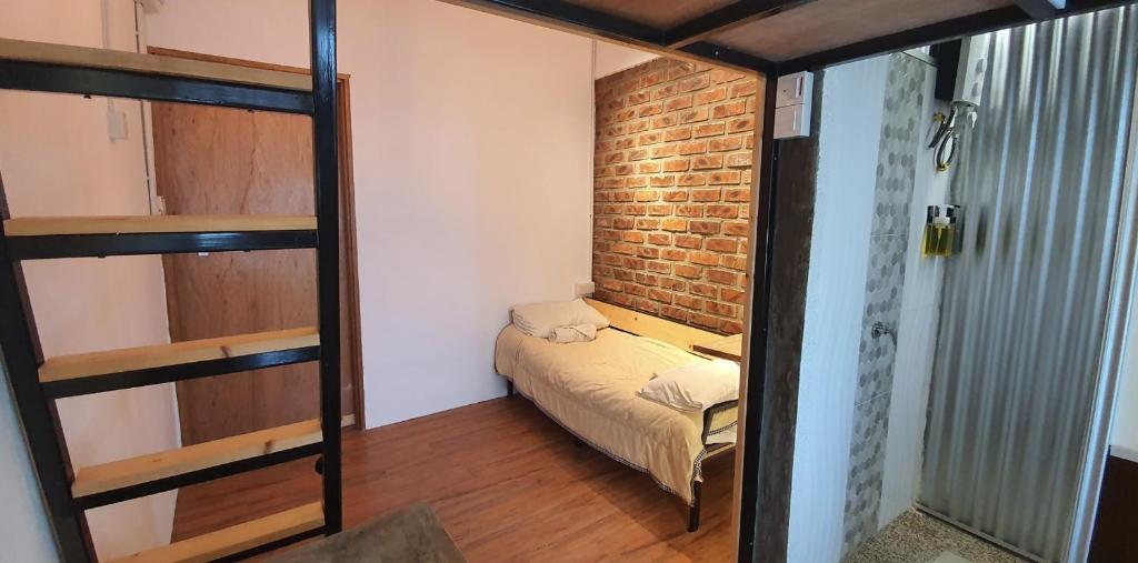 a small room with a bed and a brick wall at Tiny Home in Miri