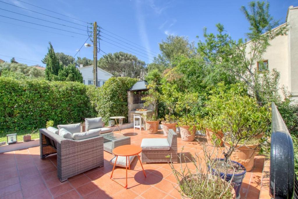 eine Terrasse mit Sofas, einem Tisch und Stühlen in der Unterkunft Elegant House With Terrace Garden And Pool in Sanary-sur-Mer