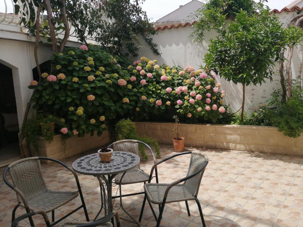 een patio met een tafel en stoelen en roze rozen bij Studio Apartments Kuljiš in Vis