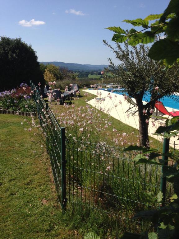 een hek voor een zwembad met bloemen bij Le gîte du mas avec piscine in Bourganeuf
