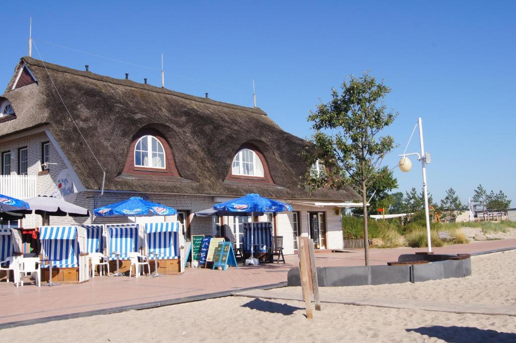 a building with blue chairs and umbrellas on the beach at Appartement im Haus Deichgraf in Dahme
