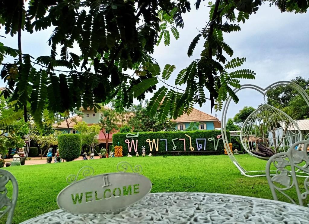 una mesa y sillas en un parque con un cartel de bienvenida en P.Paradise Hotel, en Kamphaeng Phet