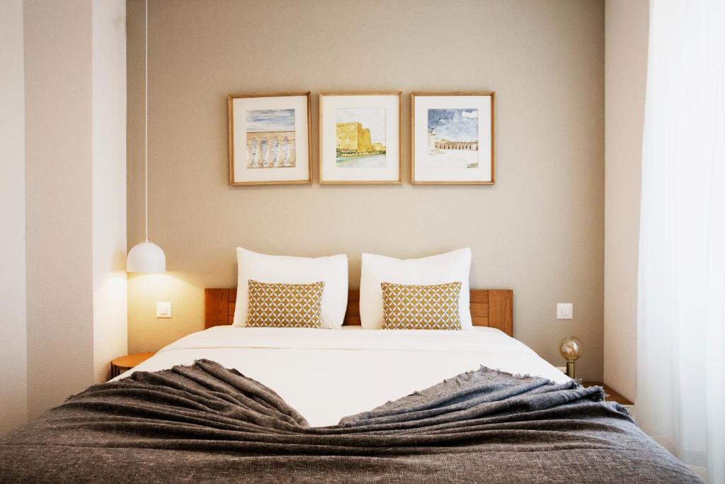 - une chambre avec un lit blanc et trois photos sur le mur dans l'établissement Vigata, à Yverdon-les-Bains