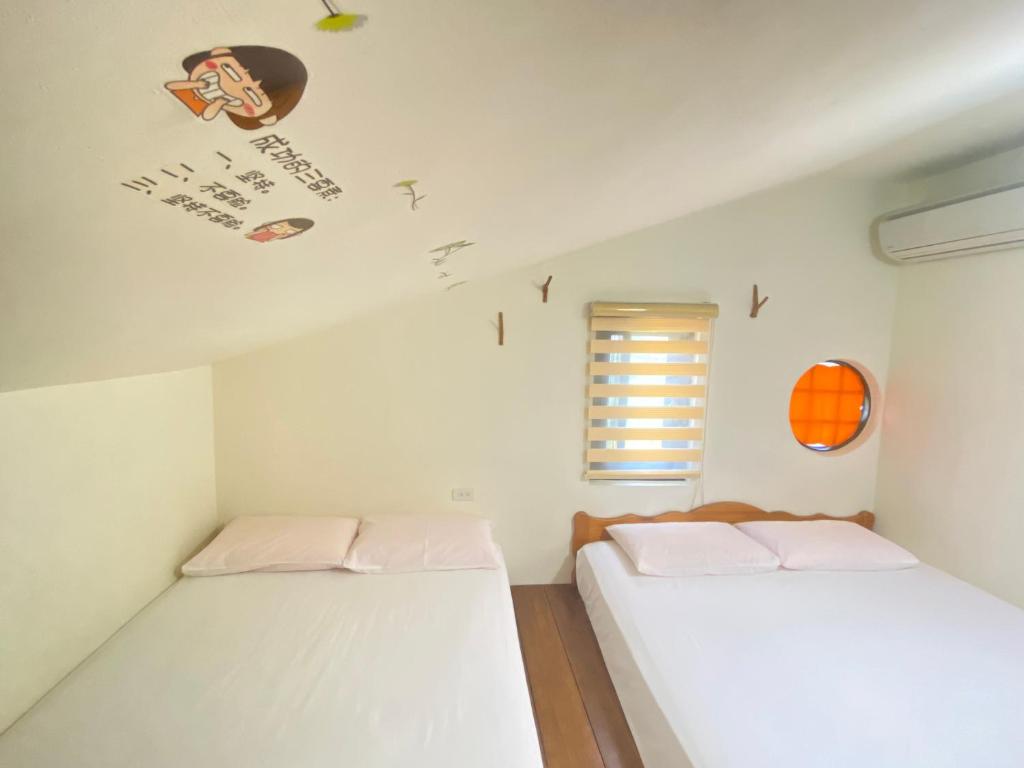two beds in a small room with a window at 金門自由行民宿 Kinmentrip B&amp;B in Jincheng