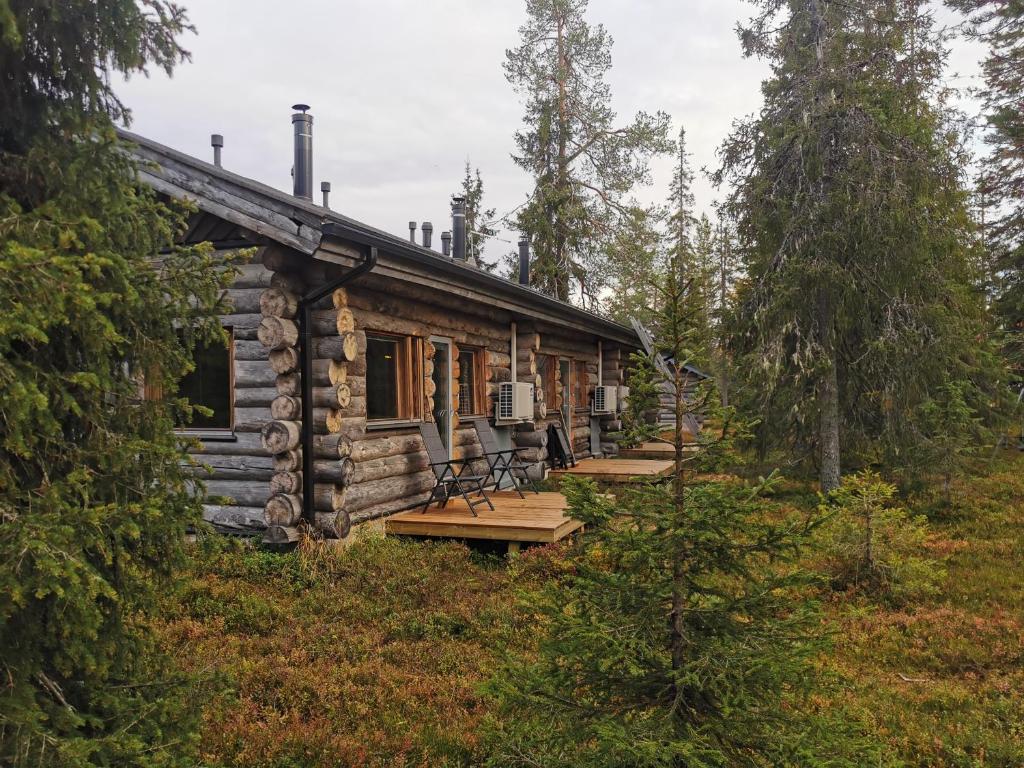 eine Blockhütte im Wald mit Bänken um sie herum in der Unterkunft Ruka Inn in Ruka