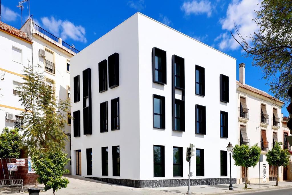 un edificio blanco con ventanas negras en una calle en Apartamentos Ribera 19 en Córdoba