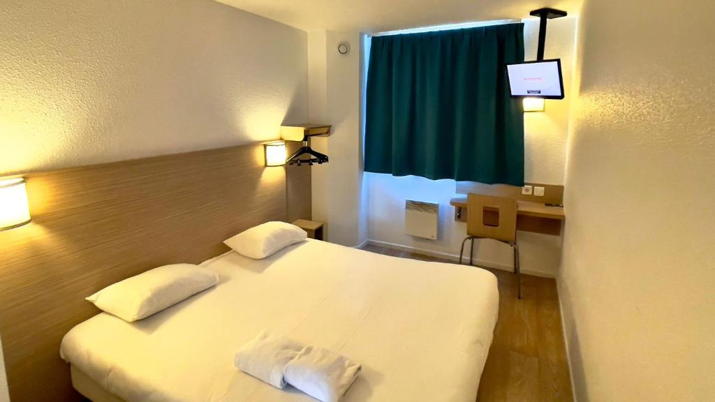 Habitación de hotel con cama blanca y escritorio en CYAN HOTEL - Roissy Villepinte Parc des Expositions en Roissy-en-France