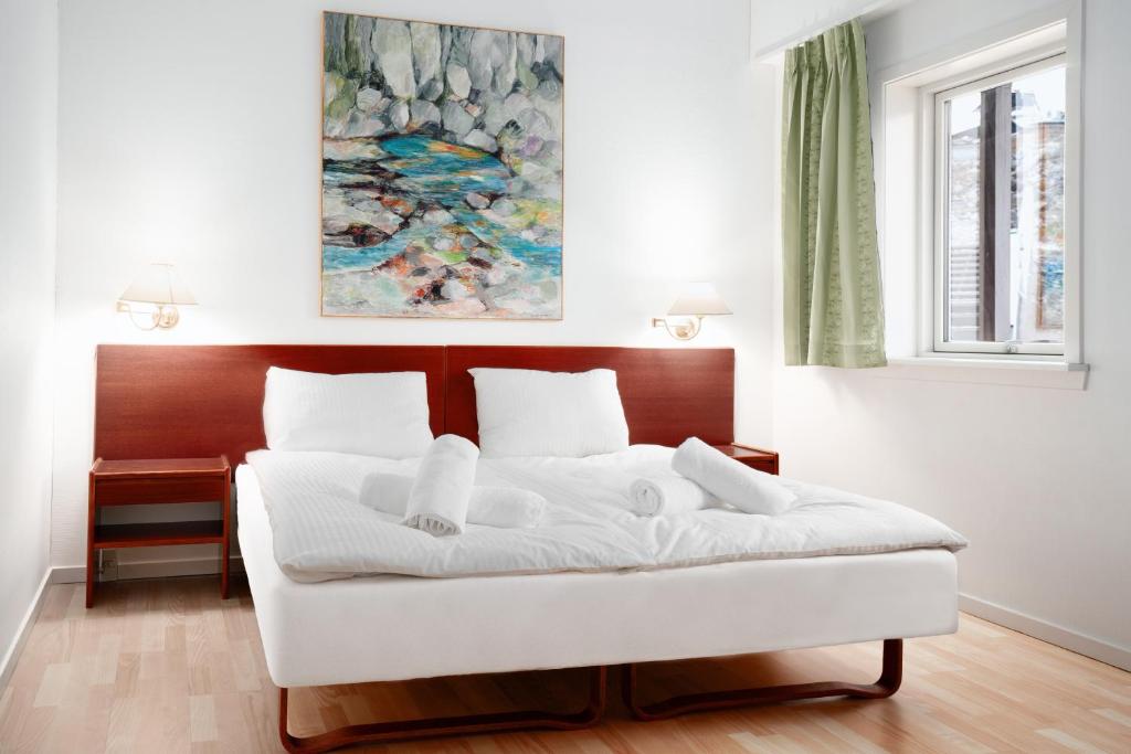 a white bed in a room with a painting at Hotel Hvide Falk in Ilulissat