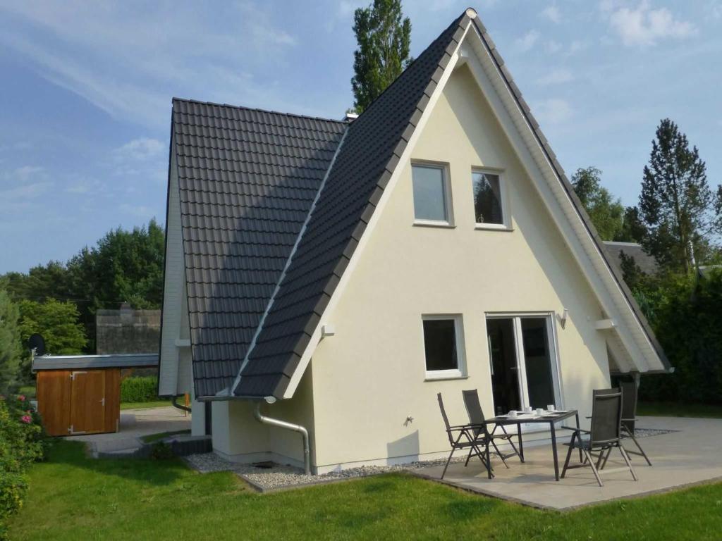 a house with a pitched roof with chairs and a table at Ferienhaus Hagebutte in Quilitz