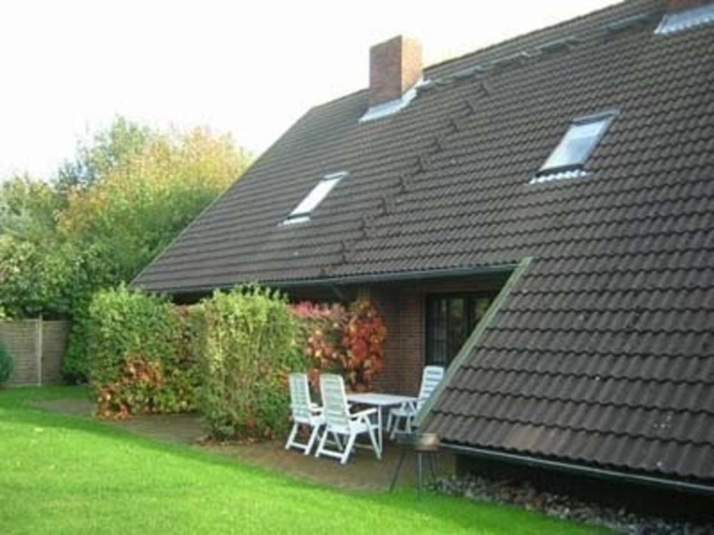 a house with two chairs and a table in the yard at Haus Schünemann 4 in Kellenhusen