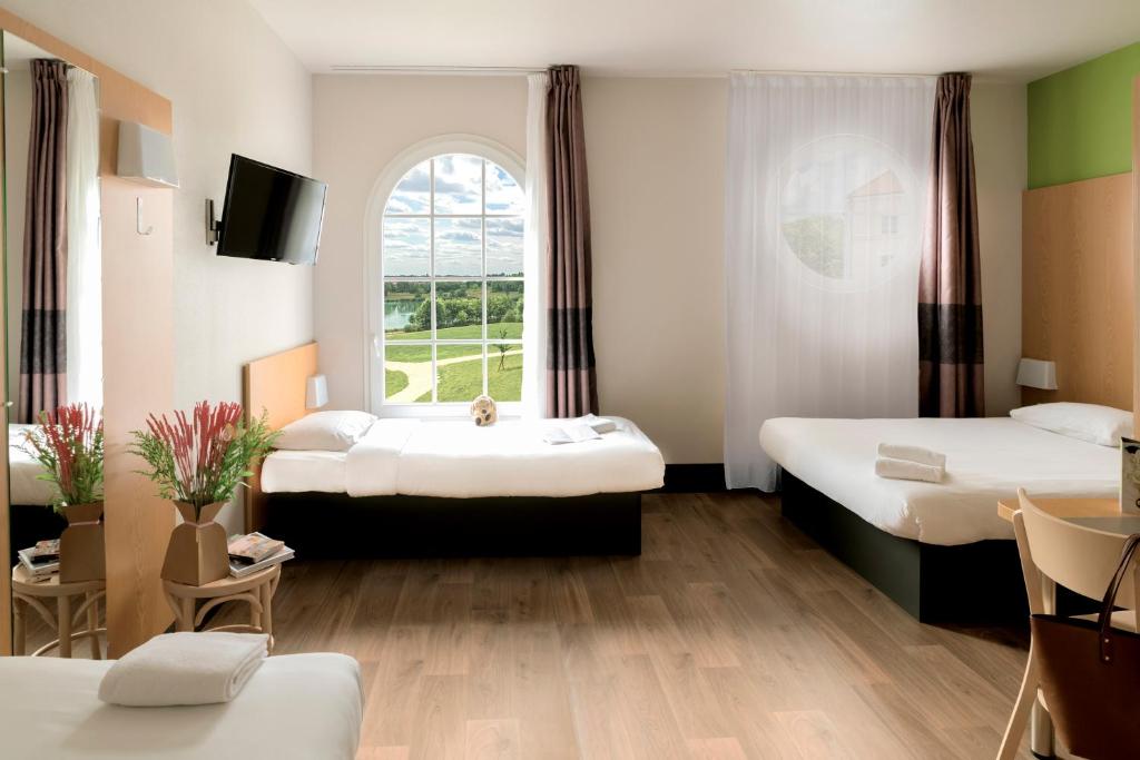 a hotel room with two beds and a window at B&B Hôtel in Magny-le-Hongre