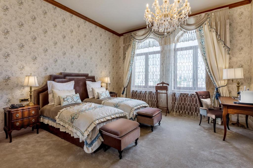 a bedroom with two beds and a desk and a chandelier at Suter Palace Heritage Boutique Hotel in Bucharest