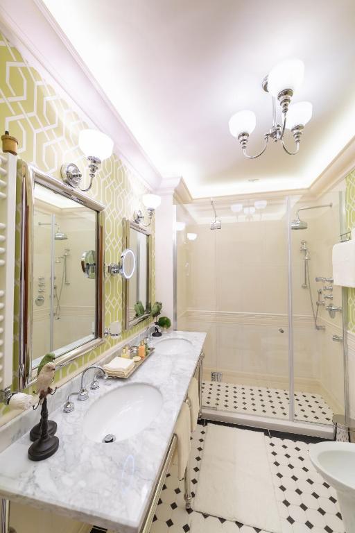 Double marble vanity with dual sinks, wall mirror and glass shower with black-and-white diamond tile at Suter Palace Heritage Boutique Hotel in Bucharest