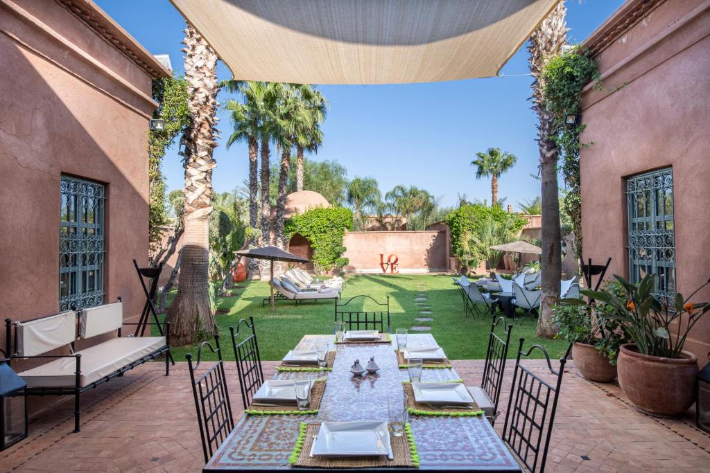 un patio al aire libre con una mesa larga y sillas en Superbe Villa Y - Calme & sureté - Piscine privée & gouvernante, en Marrakech
