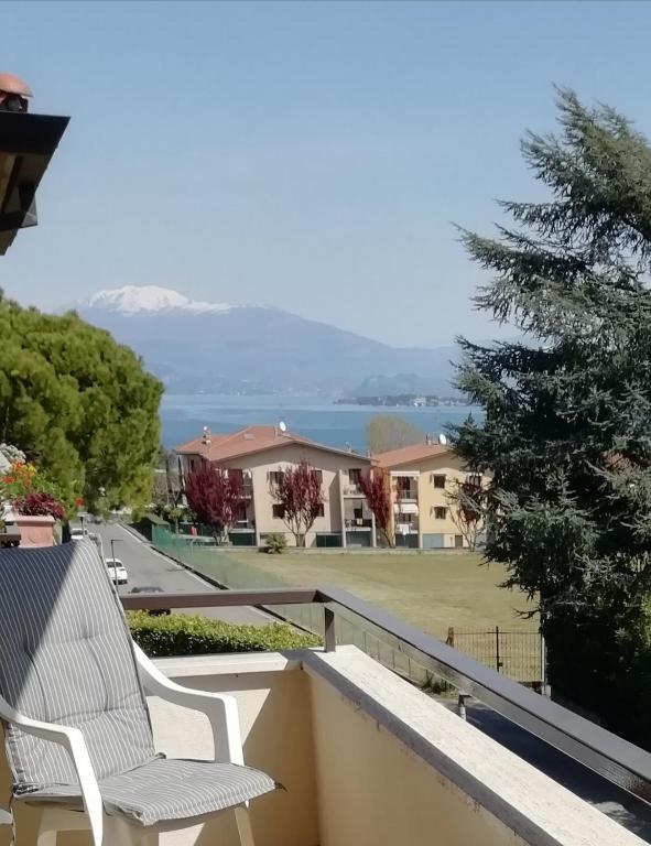 Biały fotel na balkonie z widokiem na wodę w obiekcie LovelyWillyhome w mieście Desenzano del Garda