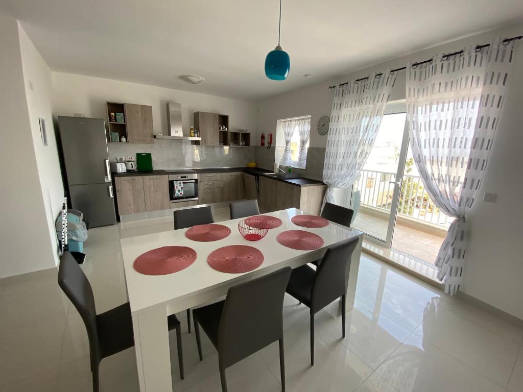 una cucina con tavolo e sedie e una sala da pranzo di Sunshine Apartments Mellieha - modern three bedroom apartment - Apt No 1 a Mellieħa