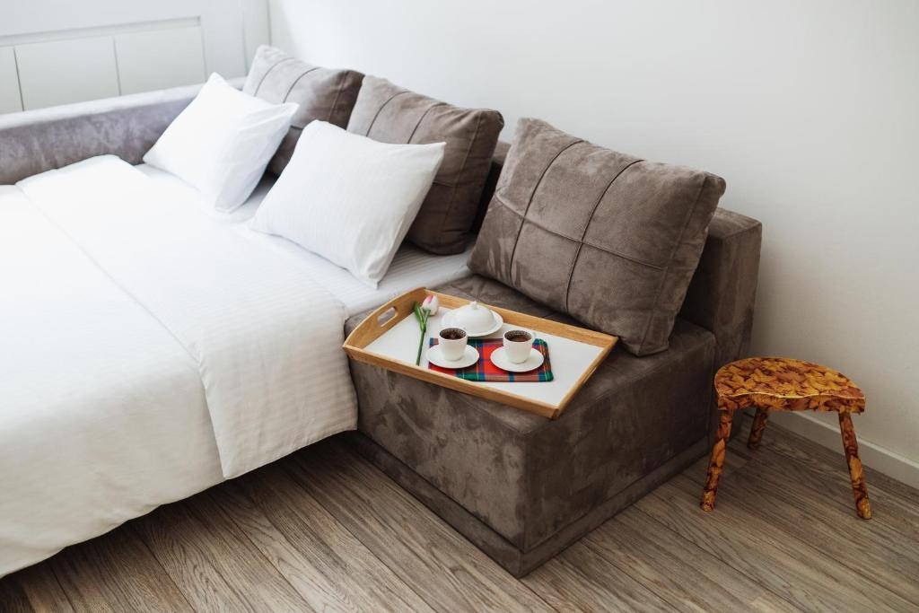 a tray with two cups and a stool next to a bed at City Center Studio in Belgrade