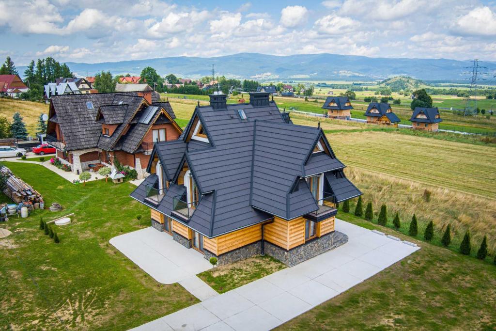 een huis met een zwart dak op een groen veld bij Apartamenty U Andzi in Białka Tatrzanska