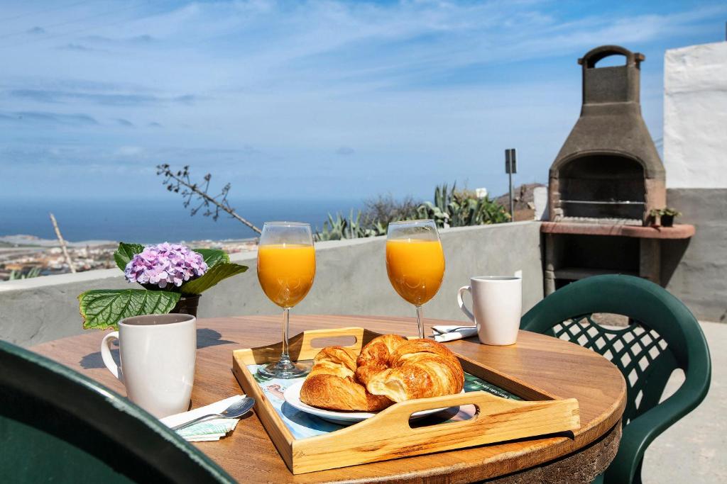 a table with a tray of bread and two glasses of orange juice at Casa Buenavista in Hoya de Pineda