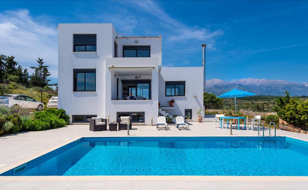 a villa with a swimming pool in front of a house at Villa Lefki in Vamos