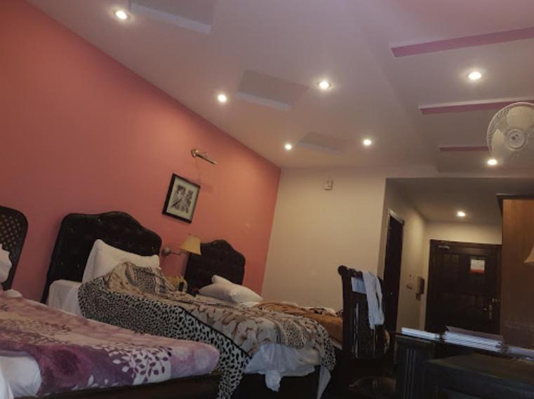 um quarto com 2 camas num quarto com paredes cor-de-laranja em Prestige Boutique Hotel & Resorts em Islamabad